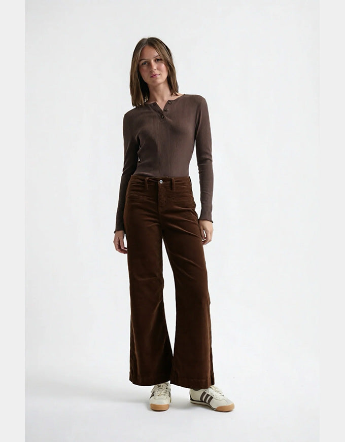 Woman wearing a brown long-sleeve top and brown wide-leg pants on a white background