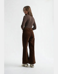 Woman wearing brown flared pants and a matching top on a white background