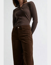 Person wearing a brown ribbed top and corduroy pants on a white background