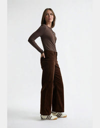 Woman wearing a brown long-sleeve top and wide-leg pants on a white background