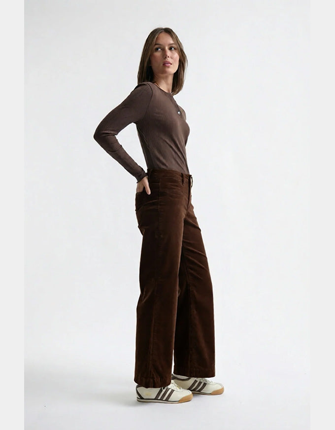 Woman wearing a brown long-sleeve top and wide-leg pants on a white background