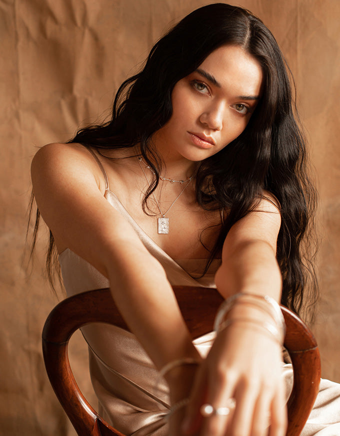 Woman sitting on a wooden chair against a warm-toned background