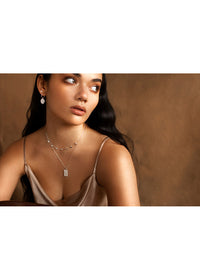 Woman wearing a necklace and earrings against a brown background