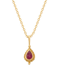 Gold necklace with a teardrop-shaped ruby pendant on a white background