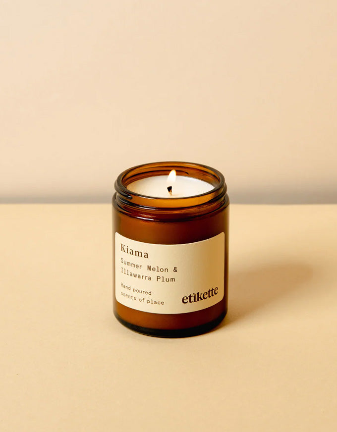 Candle in an amber jar with a label on a beige background