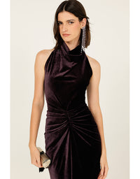 Woman wearing a dark purple halter neck dress against a plain background