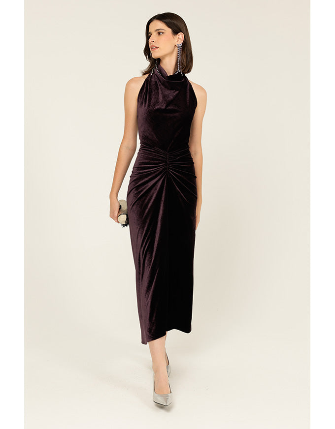 Woman wearing a dark purple halter neck dress on a white background