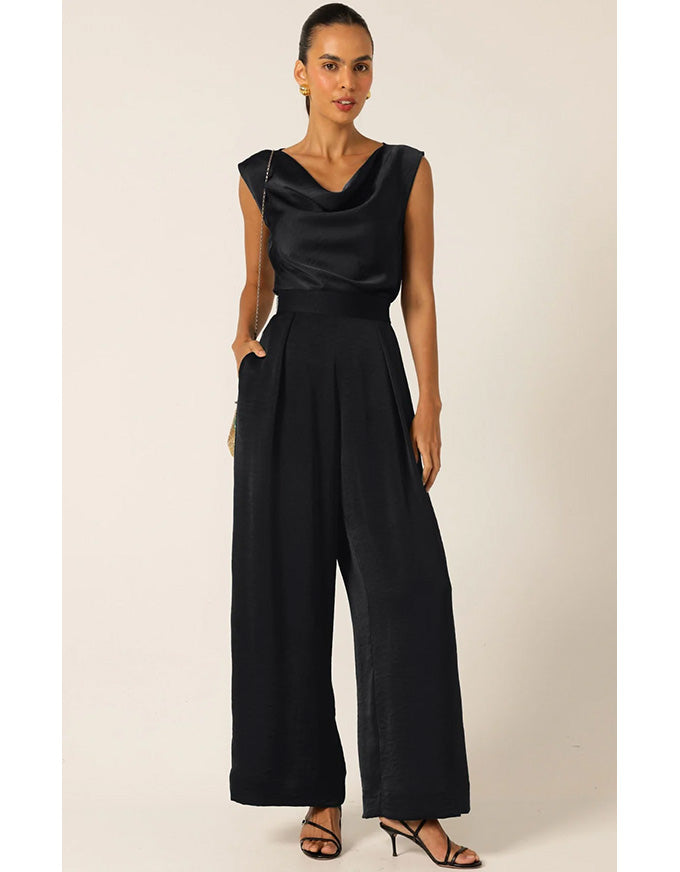 Woman wearing a black jumpsuit on a plain background