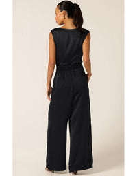 Woman wearing a black jumpsuit on a beige background