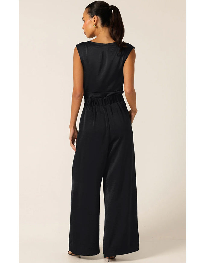 Woman wearing a black jumpsuit on a beige background