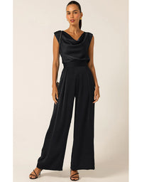 Woman wearing a black jumpsuit against a plain background