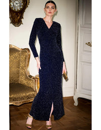 Woman in a dark blue evening gown standing in an elegant room with gold accents.