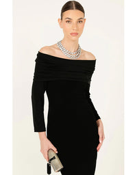 Woman wearing a black off-shoulder dress with a pearl necklace on a white background