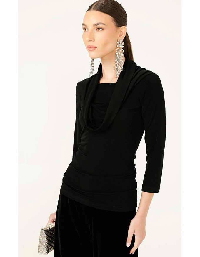 Woman wearing a black cowl-neck top with a plain background