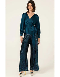 Woman wearing a teal jumpsuit with a belt on a white background