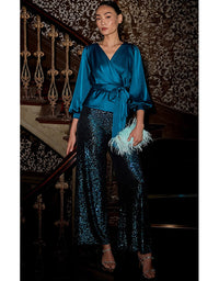 Woman in a blue top and sequin pants standing on a staircase.