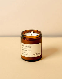 Candle in an amber jar with a label on a beige background