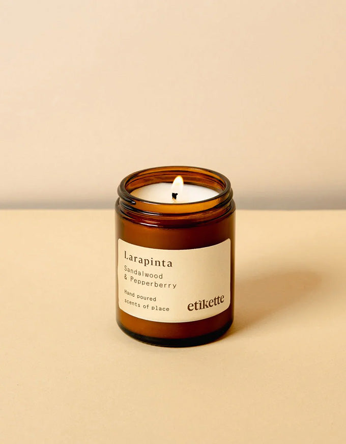 Candle in an amber jar with a label on a beige background