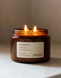 Candle in a brown jar labeled 'Larapinta' by 'etikette' on a neutral background