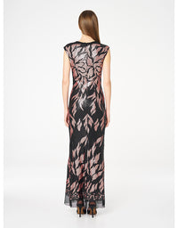 A woman viewed from the back wearing a sleeveless floor-length dress with a black base and a pink floral pattern, paired with black high heels, against a plain white studio background.