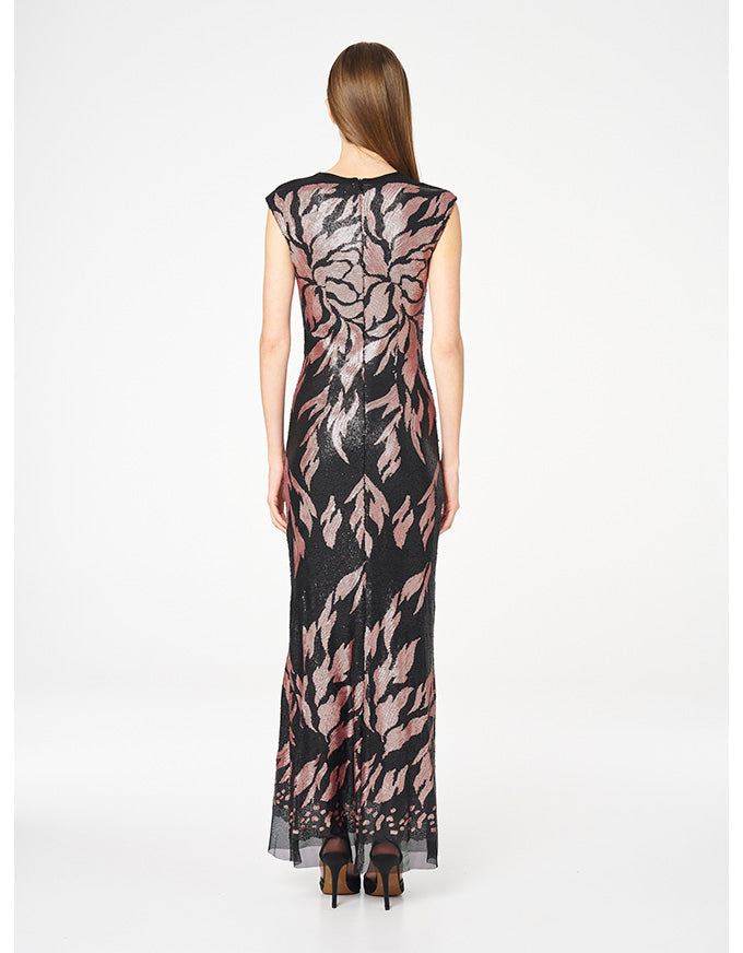 A woman viewed from the back wearing a sleeveless floor-length dress with a black base and a pink floral pattern, paired with black high heels, against a plain white studio background.