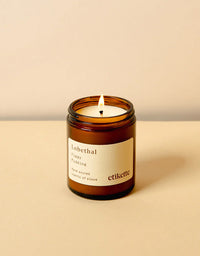 Candle in an amber jar with a white label on a beige background