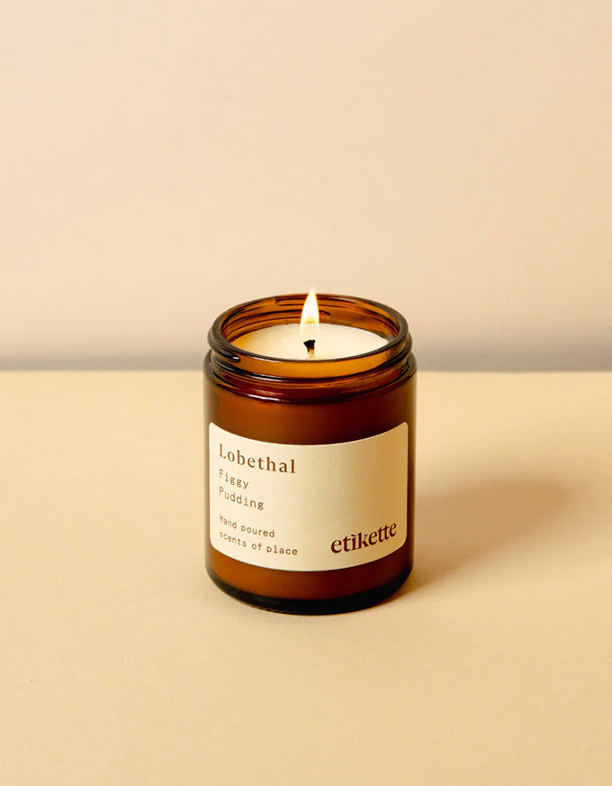 Candle in an amber jar with a white label on a beige background