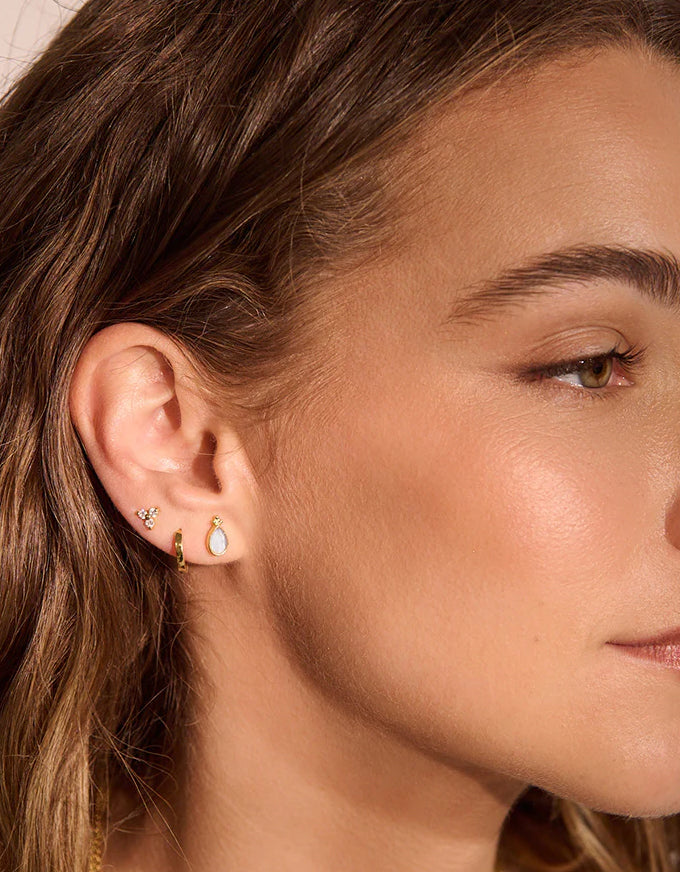 Close-up of a woman wearing gold earrings with a blurred background