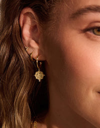 Close-up of a person wearing gold hoop earrings with a soft focus on the face.