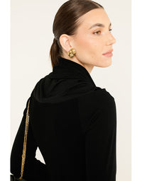 Woman wearing a black hijab with gold accents on a white background