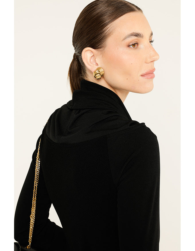 Woman wearing a black hijab with gold accents on a white background