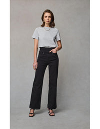 Woman wearing a gray t-shirt and black pants against a plain background
