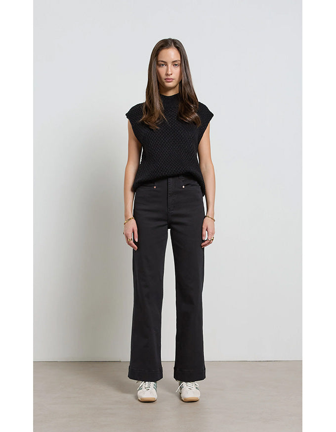 Woman wearing a black sleeveless top and black pants against a white background