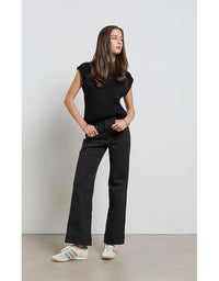 Woman wearing a black sleeveless top and black pants against a white background