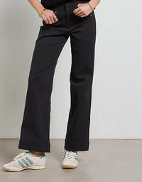 Person wearing black pants and white sneakers on a plain background
