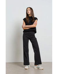 Person wearing a black outfit standing against a plain background
