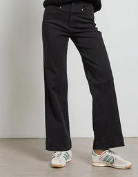 Person wearing black pants and white sneakers on a plain background