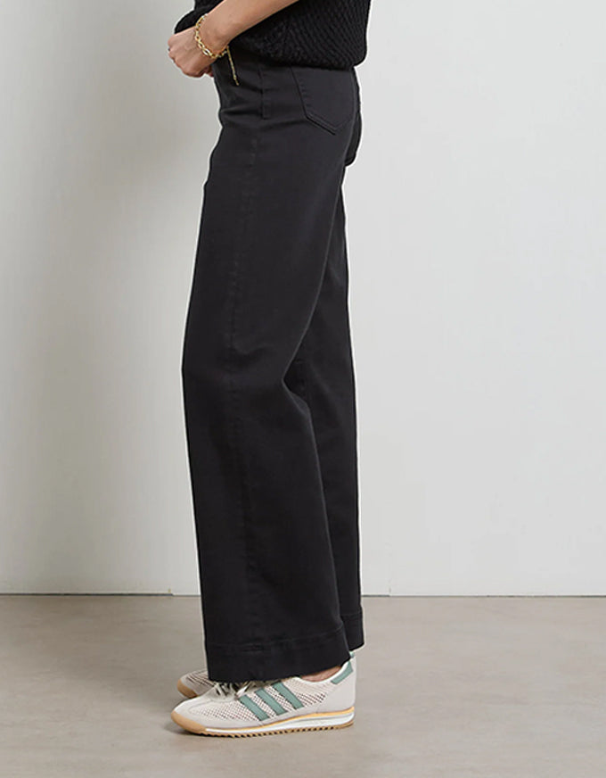 Person wearing black wide-leg pants with a plain background