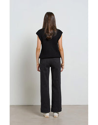 Woman wearing a black sleeveless top and black pants against a white background
