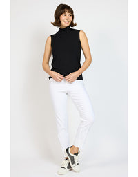 Woman wearing a black sleeveless top and white pants on a light gray background