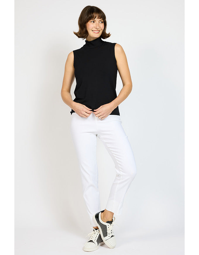 Woman wearing a black sleeveless top and white pants on a light gray background