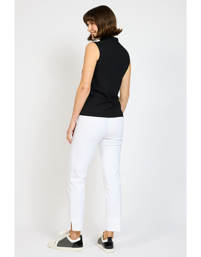 Woman wearing a black sleeveless top and white pants on a plain background