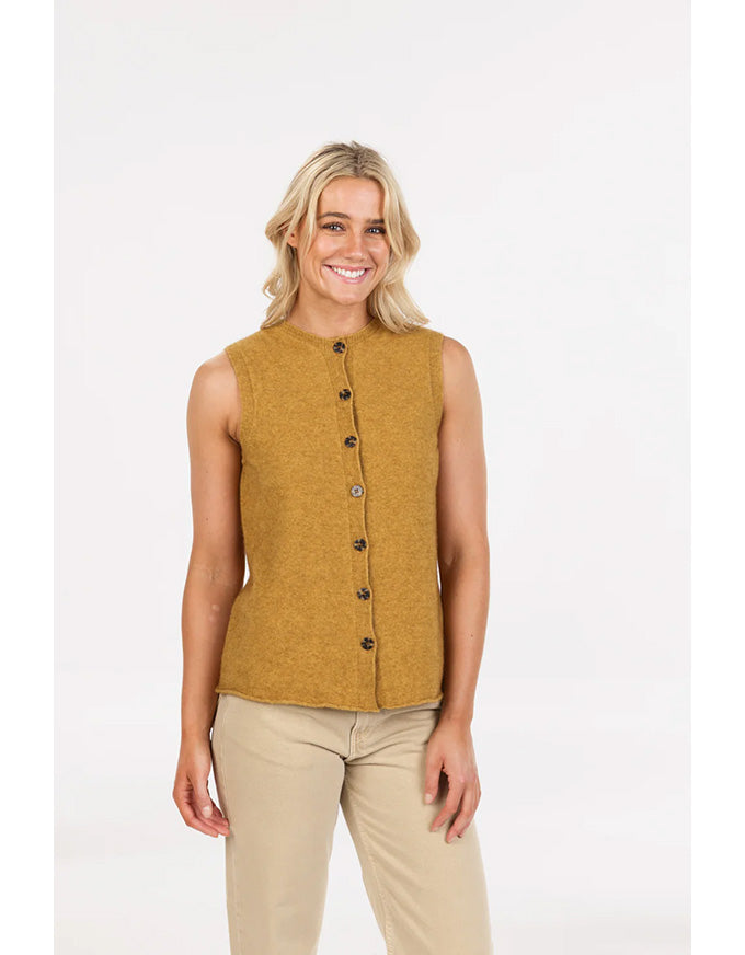 Woman wearing a mustard yellow sleeveless top with buttons on a white background