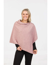Woman wearing a pink poncho over a black top and pants on a white background