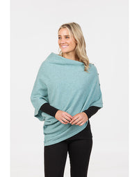 Woman wearing a light blue poncho over a black top and pants on a white background