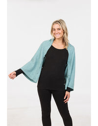 Woman wearing a light blue cardigan over a black top and pants on a white background