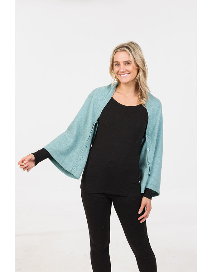Woman wearing a light blue cardigan over a black top and pants on a white background