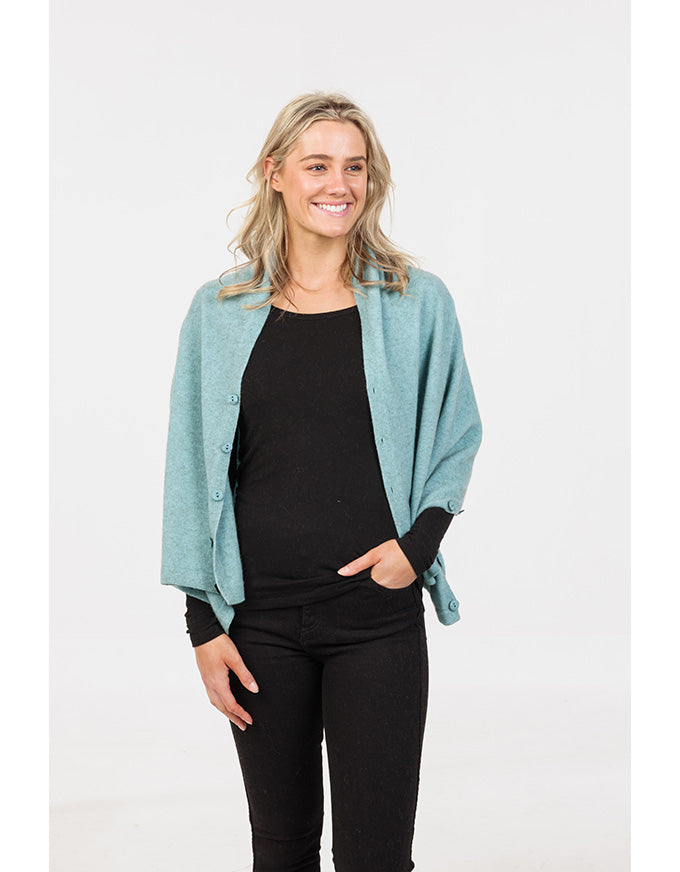 Woman wearing a light blue cardigan over a black top and pants on a white background