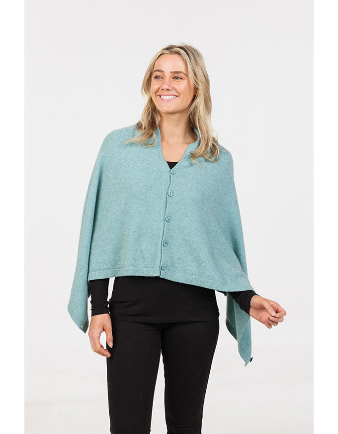 Woman wearing a teal poncho over a black outfit on a white background