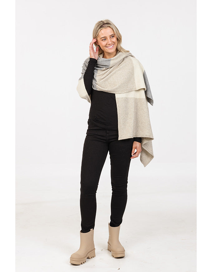 Woman wearing a beige shawl over a black outfit on a white background